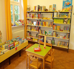 Innenansicht der Pfarrbücherei Maria Schutz mit Bücherregal und Tisch und Stühle für Kinder
