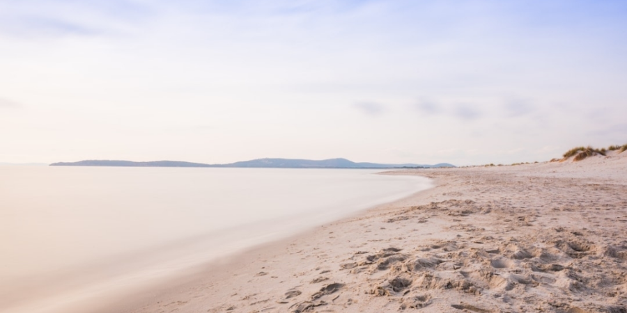 Fußspuren im Sand am Meer in leichten Pastelllicht
