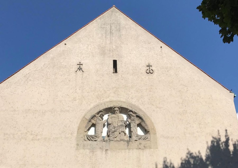 Vorderfront der Kirche: über dem Eingang ist ein Außenrelief mit dem segnenden Christus dargestellt.