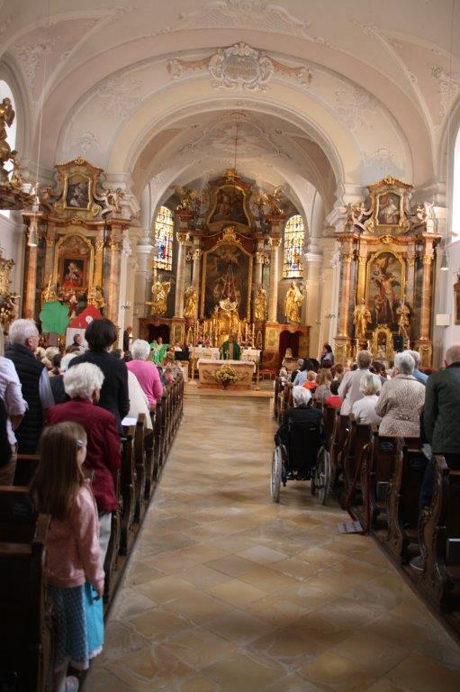 Man sieht den Mittelgang mit Blick auf den Hochaltar und die vollbesetzten Kirchenbänke