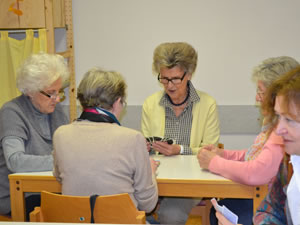 4 Damen sitzen an einem Tisch und spielen Karten