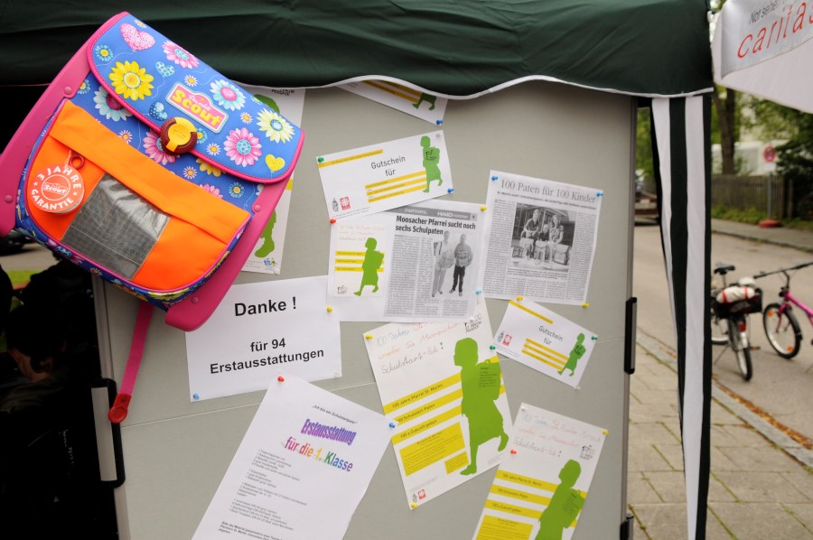 Pinwand mit Zeitungsartikeln und einem Schulranzen zeigt den Abschluss der Aktion Schulerstausstattung für bedürftige Familien