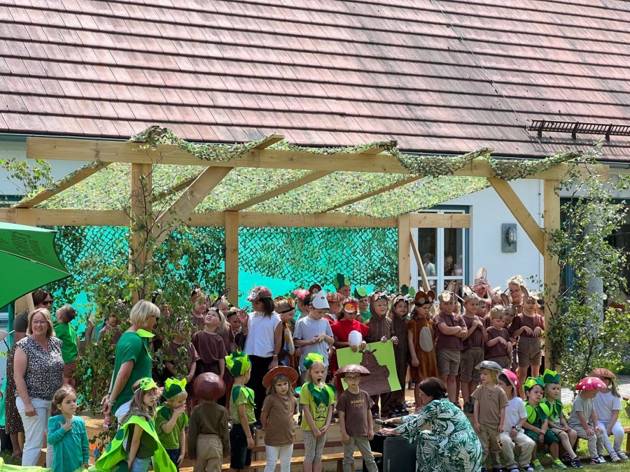 Alle Kinder auf der als Wald gestalteten Bühne zum Gruppenbild bei der Aufführung des "Grüffelo" auf bayrisch