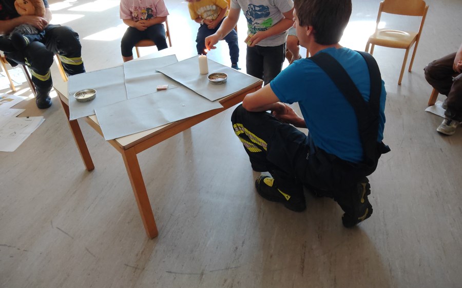 Die Kinder üben mit dem Feuerwehrmann.