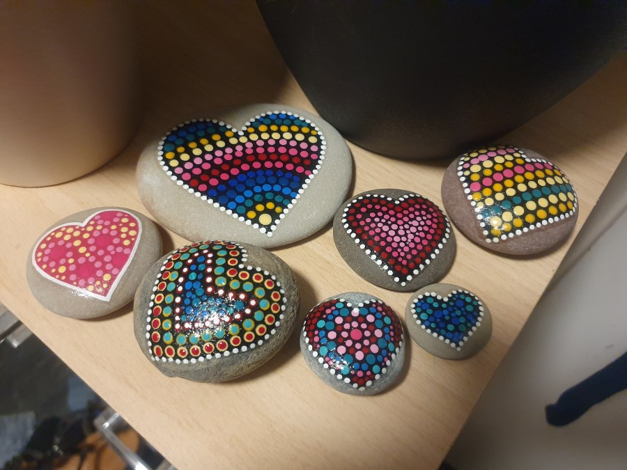 runde Steine bemalt jeweils mit einem Herz aus bunten Punkten