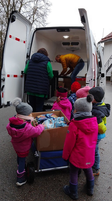Kinderhausleitung Frau Rott räumt die gespendeten Lebensmittel und Hygieneartikel mit den Kindern in den Transporter der Tafel Erding.