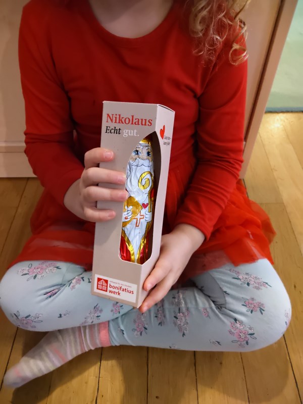 Ein Kind hält einen Bischof Nikolaus aus Schokolade in den Händen.