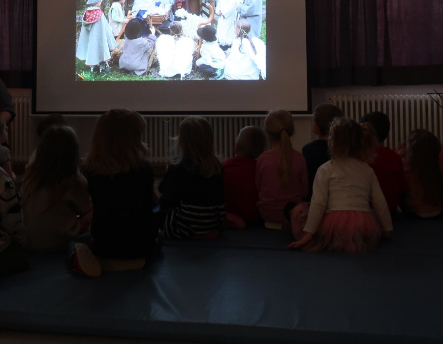 Die Kinder betrachten die Präsentation der Weihnachtsgeschichte, die die Vorschulkinder im Rahmen eines Fotoprojektes nachgestellt haben.