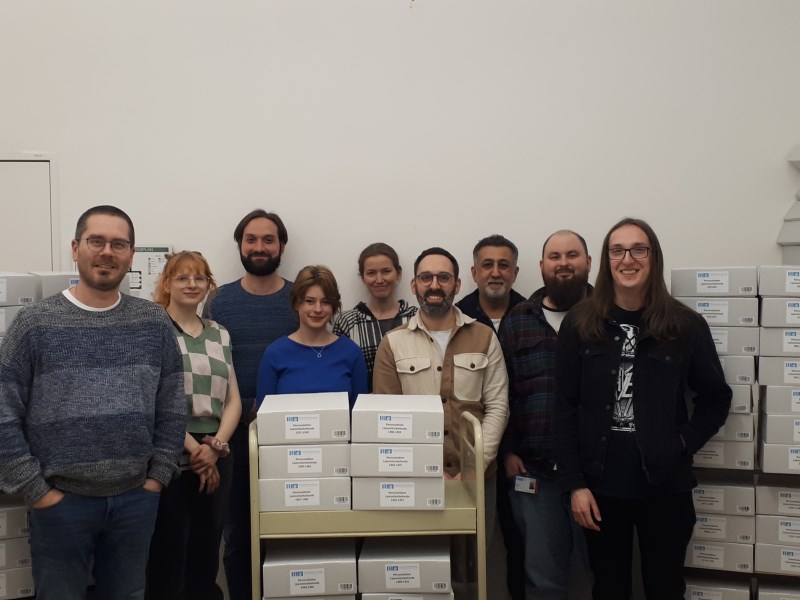 Die Archiv-Anwärter:innen mit ihrem Praktikumsbetreuer, Archivleiter Michael Volpert, und einem Teil der bearbeiteten Akten