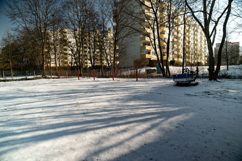 Große, verschneite Freispielfläche der KiTa St. Lukas inmitten von Hochhäusern