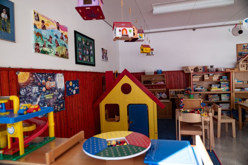 Spielecke mit Spielhaus, Tisch und Regale mit verschiedenen Spielsachen in der Kita St. Lukas