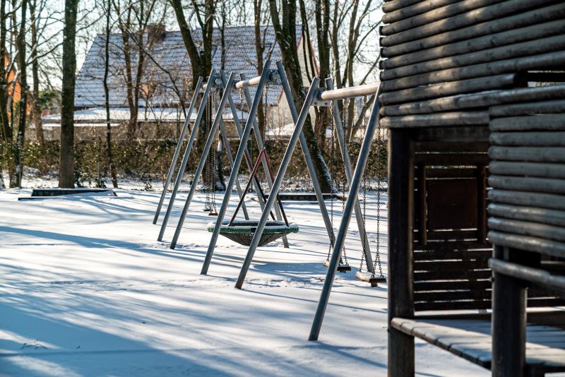 Schaukeln in der verschneiten Freispielfläche der Kita St. Markus