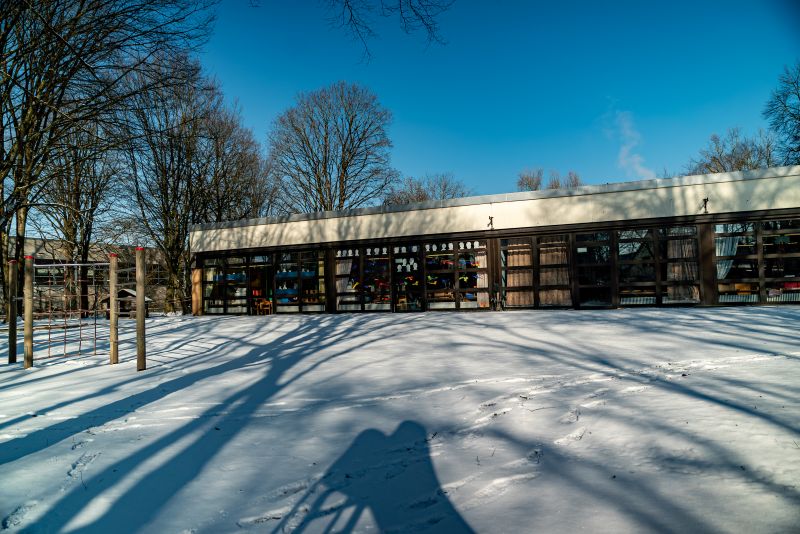 Außenansicht des flachen Kita-Gebäudes von St. Markus mit verschneiter Gartenfläche