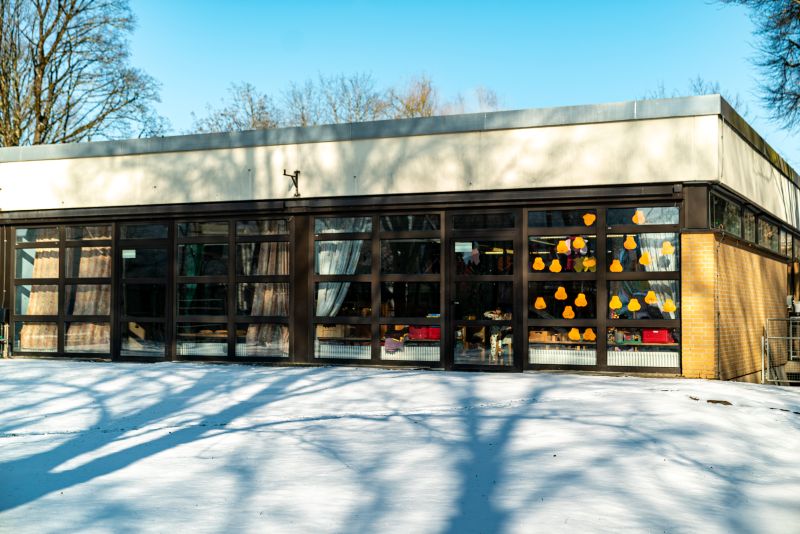 Außenansicht des flachen Kita-Gebäudes von St. Markus mit verschneiter Gartenfläche