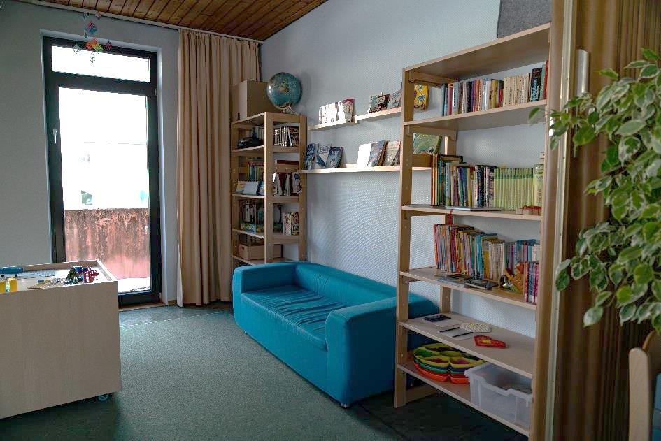 Kuschlige Leseecke mit blauer Couch und zwei Bücherregalen im Kinderhaus Maria Schutz