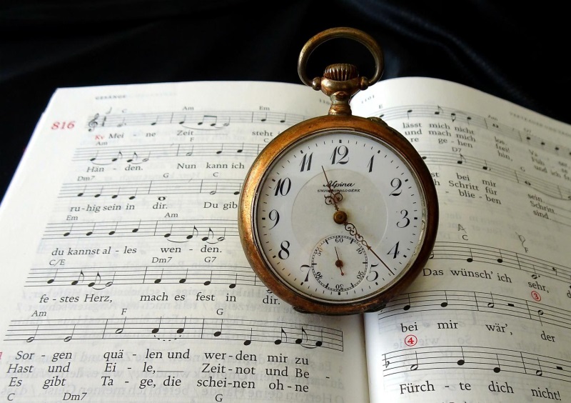 Eine alte Taschenuhr liegt auf einem geöffneten Gotteslob-Buch.