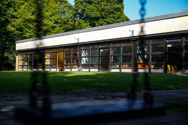 (Unscharfer) Schaukelsitz, dahinter das Flachgebäude der Kita St. Markus