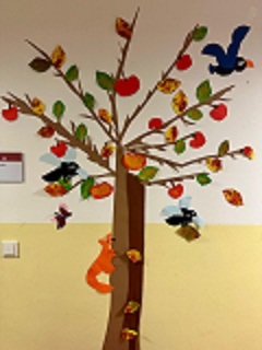 großer Baum im Herbst mit gebastelten Blättern, Früchten und Tieren