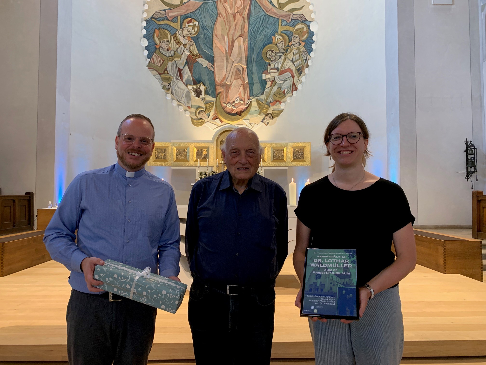 Pfarrer Alois Emslander und Pastoralreferentin Agnes Huber erreichen ein Geschenk im Namen des Pfarrverbands