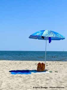 Sonnenschirm im Sandstrand und Blick auf das Meer