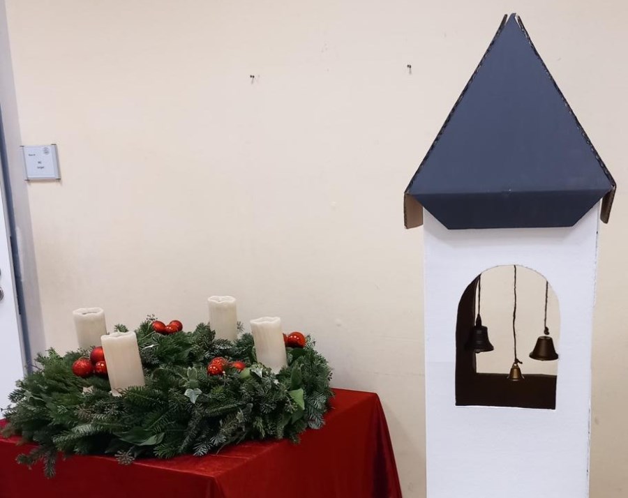 gebastelter Glockenturm steht neben Adventskranz