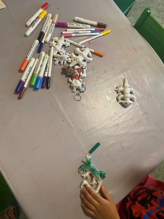Buntstifte und gebastelte Geckos liegen auf einem Tisch