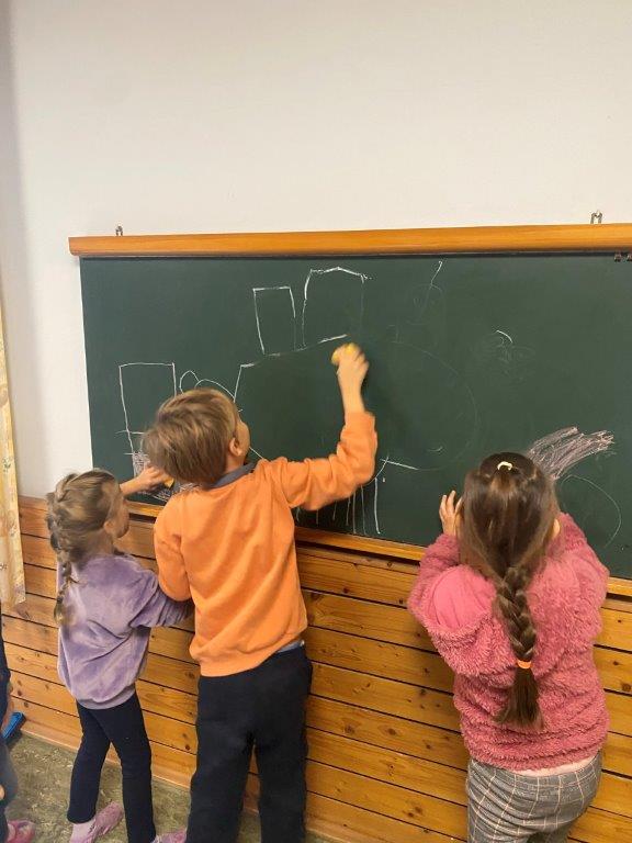 Kinder malen auf einer Schultafel