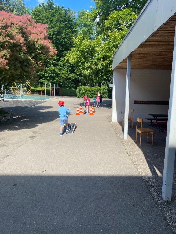 Kinder fahren mit ihrem Roller einen Parcours