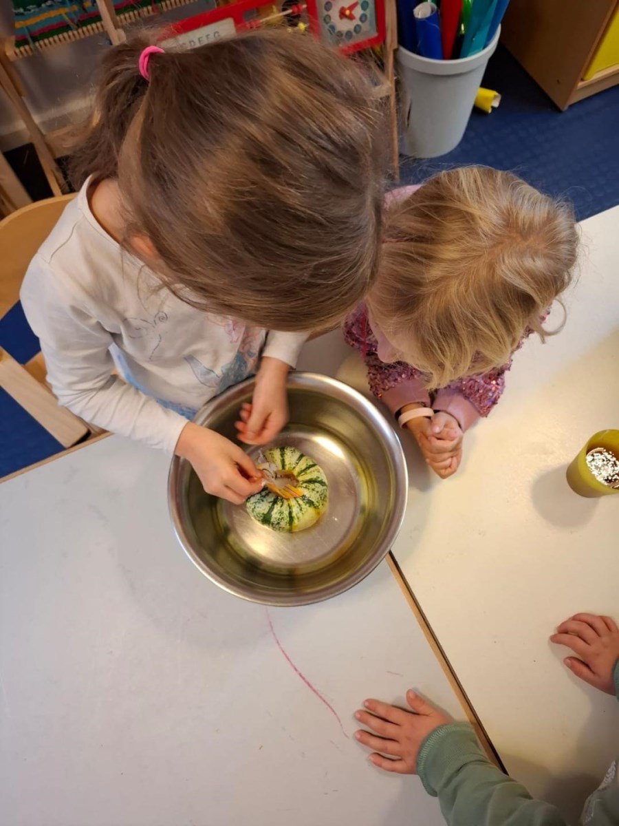Kind schüttet Backpulver zu Kürbis